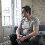 40er oder 50er Jahre traurig und besorgt Mann mit grauen Haaren sitzt zu Hause Couch suchen deprimiert und verschwendet in Traurigkeit Gesichtsausdruck in Depression und Leben Probleme Konzept